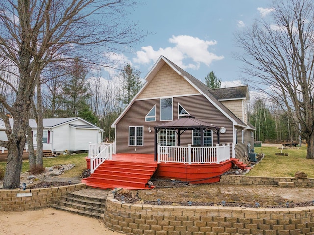 1219 Nokomis Dr, Gladwin, MI 48624 - rustic home featuring a wooden deck, a gazebo, a shingled roof, and a front lawn