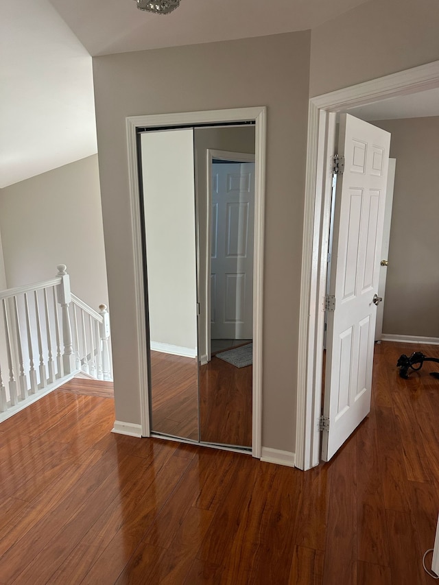 interior space with baseboards, wood finished floors, and an upstairs landing