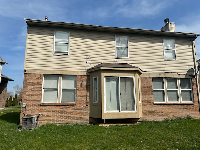 back of house with brick siding, central air condition unit, a yard, and a chimney