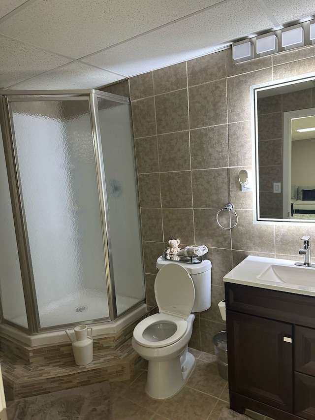 full bath with tile walls, toilet, a stall shower, tile patterned flooring, and vanity