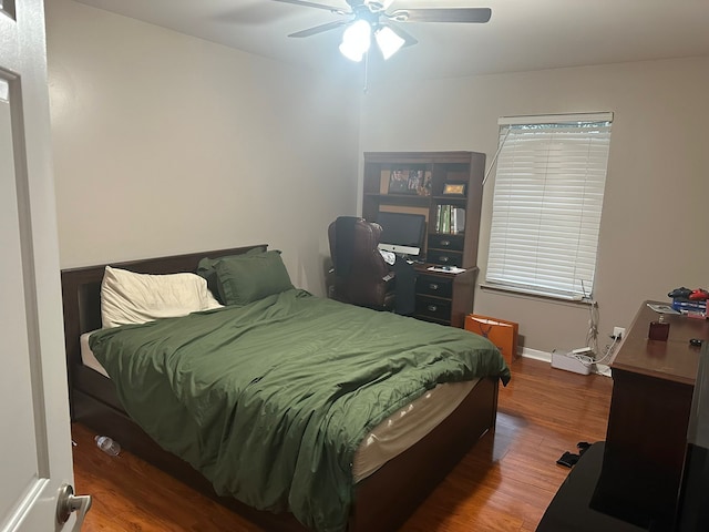 bedroom featuring wood finished floors, a desk, a ceiling fan, and baseboards