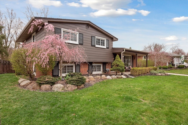 view of front of house featuring brick siding, fence, and a front yard