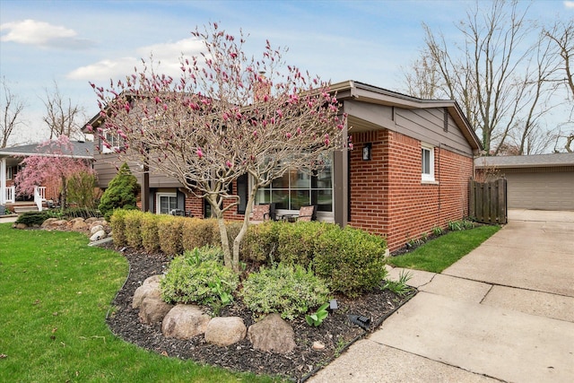 view of front of house featuring brick siding, a front lawn, and a garage