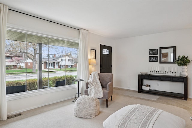 living area with baseboards, visible vents, and carpet floors