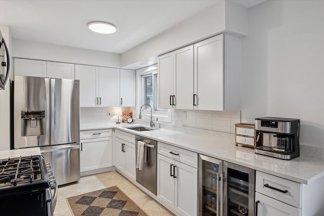 kitchen with wine cooler, a sink, white cabinetry, backsplash, and appliances with stainless steel finishes