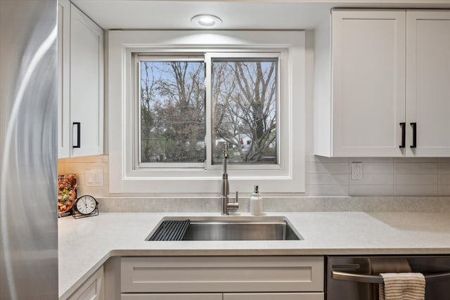 kitchen featuring white cabinets, dishwasher, light countertops, and a sink