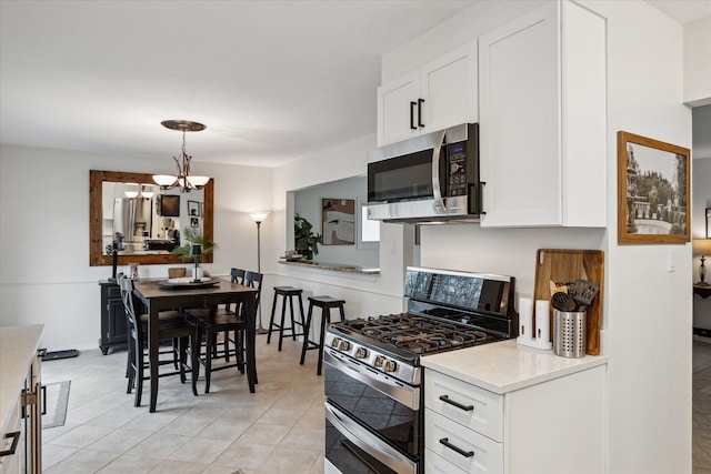 kitchen with white cabinets, a notable chandelier, stainless steel appliances, and light tile patterned floors