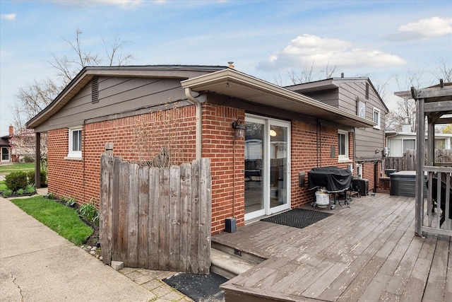 view of home's exterior with fence, a wooden deck, and brick siding