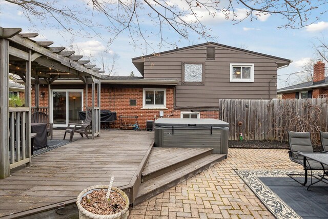 wooden deck with a pergola, a hot tub, a patio, and fence