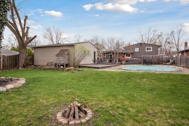 view of yard with an outdoor fire pit, a fenced backyard, a fenced in pool, and a deck
