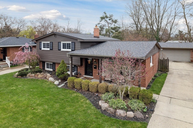 split level home featuring a chimney, a front lawn, roof with shingles, covered porch, and brick siding