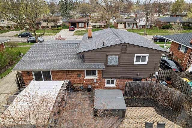 back of house with brick siding, a residential view, a shingled roof, and a fenced backyard