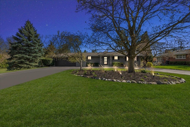 view of front of property featuring an attached garage, a front lawn, and aphalt driveway