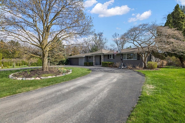 ranch-style home with a front lawn, aphalt driveway, and a garage