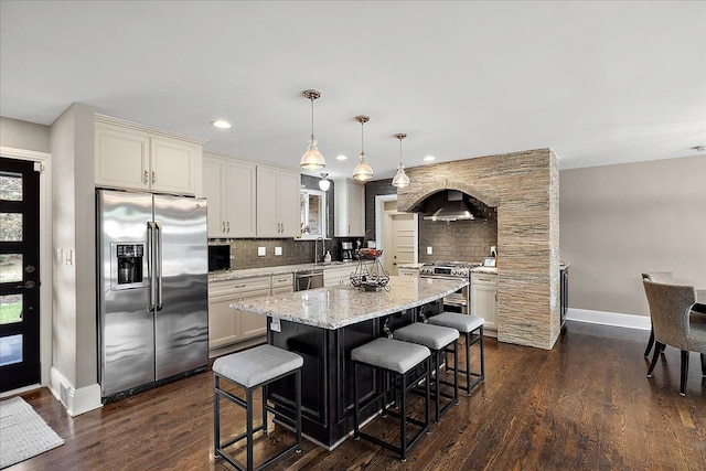 kitchen with a center island, a breakfast bar area, backsplash, baseboards, and appliances with stainless steel finishes