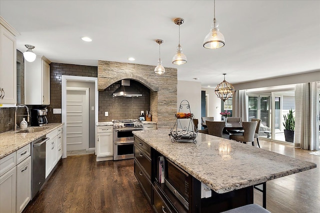 kitchen featuring a sink, decorative backsplash, a breakfast bar area, appliances with stainless steel finishes, and dark wood-style floors