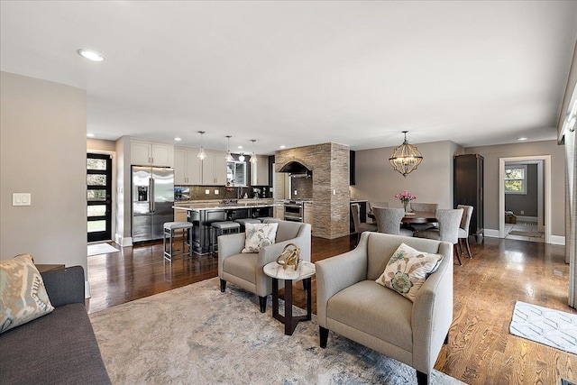 living area featuring baseboards, wood finished floors, recessed lighting, and a chandelier