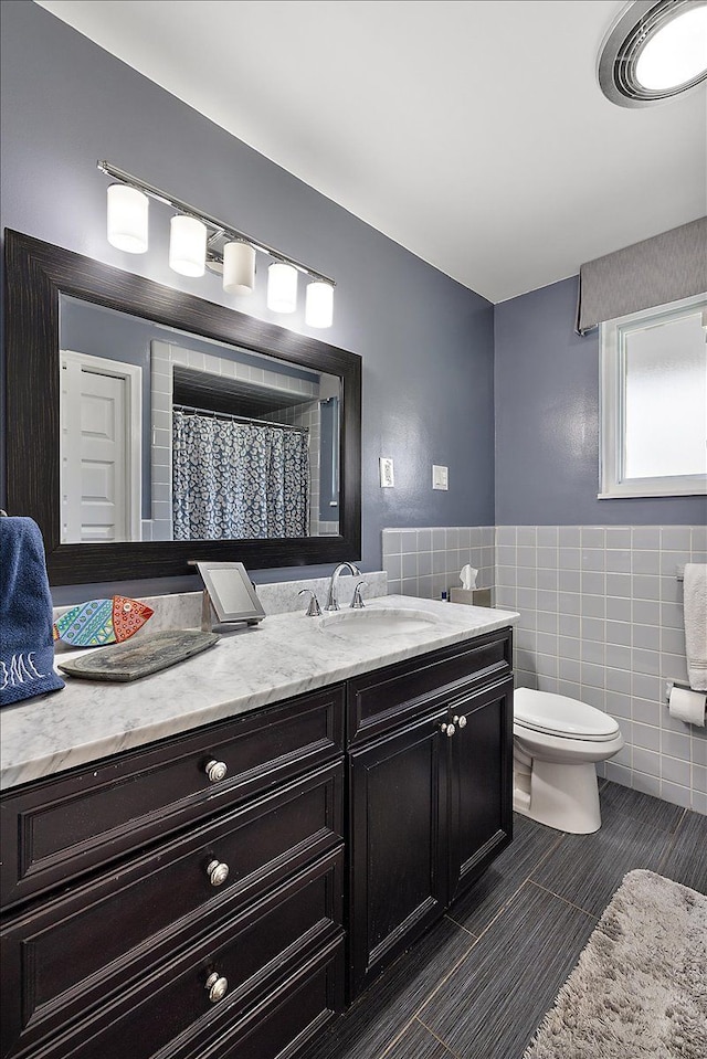 bathroom featuring tile walls, vanity, visible vents, and toilet