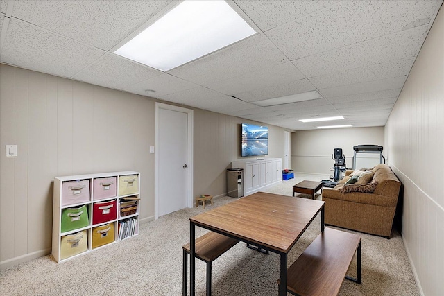 carpeted living area with a paneled ceiling