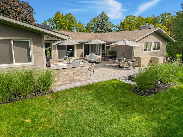 rear view of property featuring a chimney, a yard, a patio, an outdoor living space, and roof with shingles