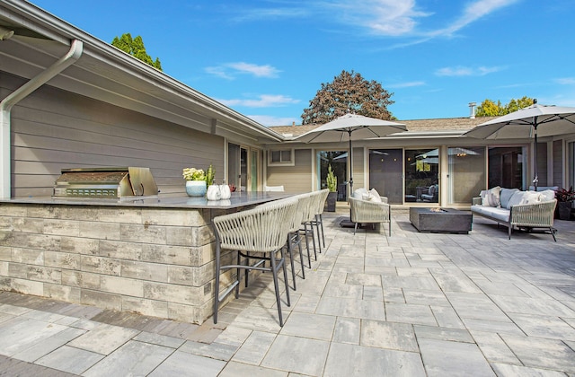 view of patio with exterior bar, an outdoor living space with a fire pit, and area for grilling