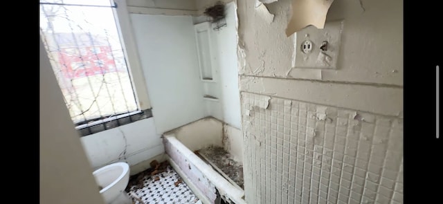 bathroom featuring toilet, walk in shower, a tub, and tile walls