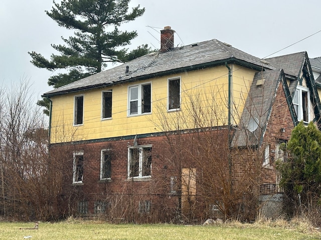 view of home's exterior featuring a chimney and roof with shingles