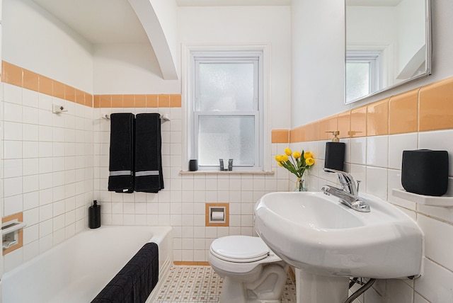 full bath with a wainscoted wall, a sink, a bathtub, toilet, and tile walls