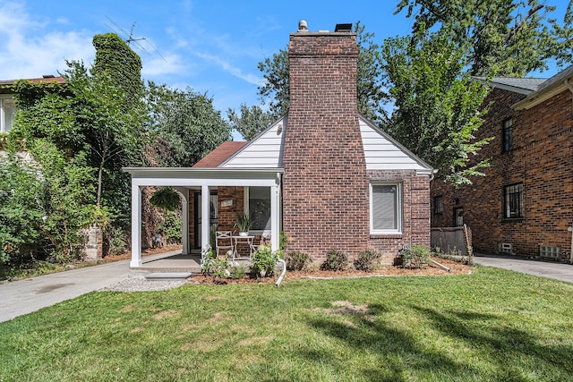 exterior space featuring brick siding, a lawn, and a chimney