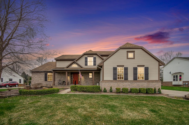 view of front of home featuring a porch, a lawn, brick siding, and roof with shingles