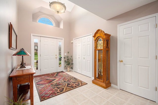 entryway featuring baseboards, light tile patterned flooring, and a high ceiling