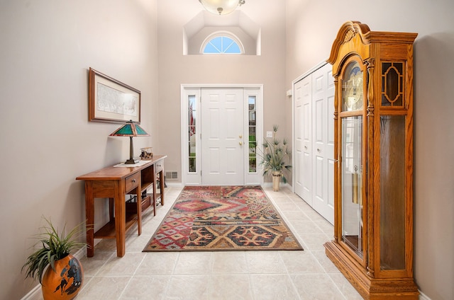 entrance foyer with light tile patterned flooring, a high ceiling, baseboards, and visible vents