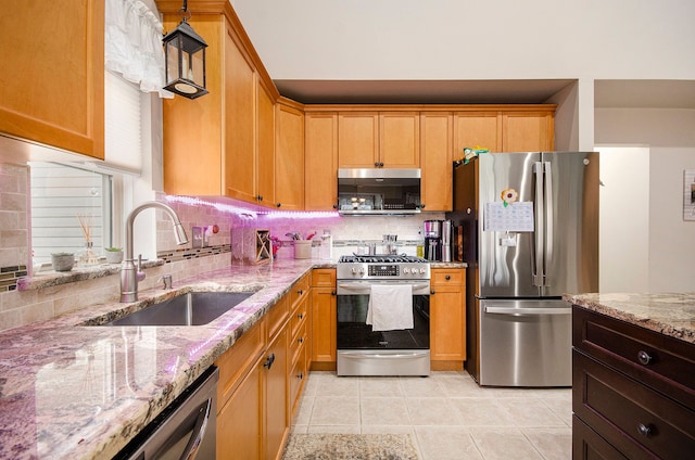 kitchen featuring tasteful backsplash, a sink, light tile patterned floors, stainless steel appliances, and light stone countertops