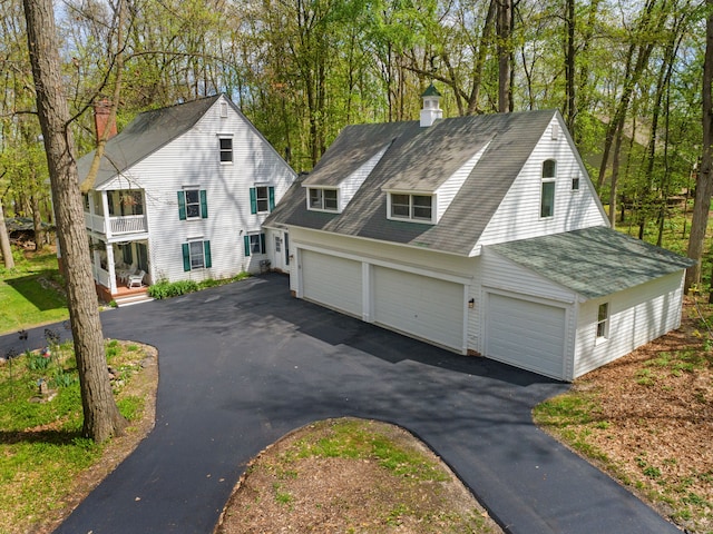 2457 Rocky Top Ln, Commerce Twp, MI 48382 - view of front of house featuring a chimney, driveway, a balcony, and roof with shingles