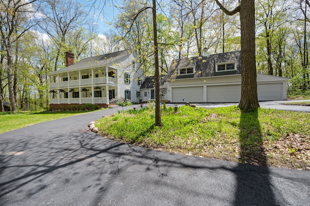 2457 Rocky Top Ln, Commerce Twp, MI 48382 - view of front of house featuring a chimney, a garage, a balcony, driveway, and a front lawn