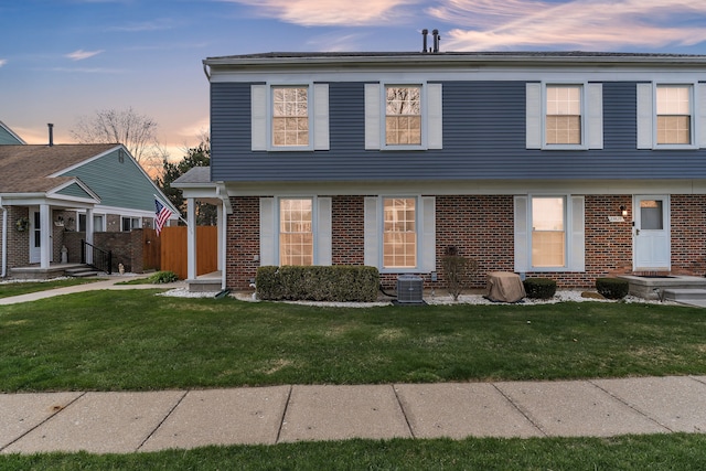 view of front facade with fence, brick siding, and a front yard