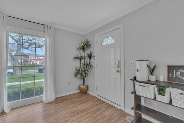 foyer featuring baseboards, ornamental molding, wood finished floors, and visible vents