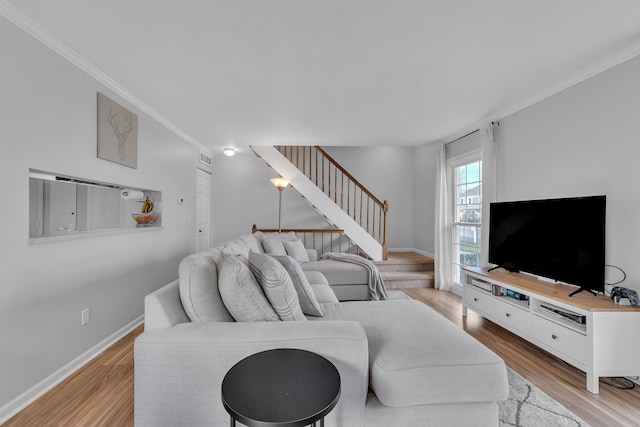 living room featuring baseboards, light wood-style flooring, crown molding, and stairs