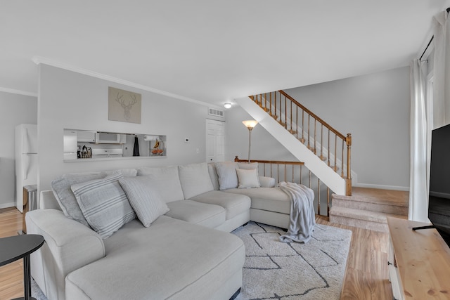 living area featuring visible vents, baseboards, wood finished floors, stairway, and ornamental molding