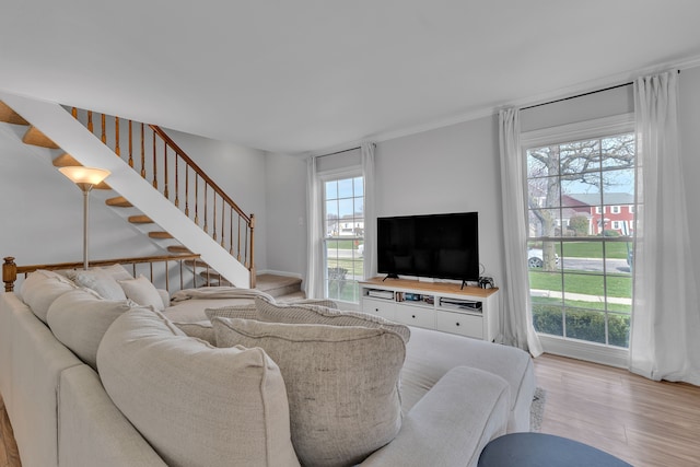 living area featuring light wood-style flooring, stairway, and a healthy amount of sunlight