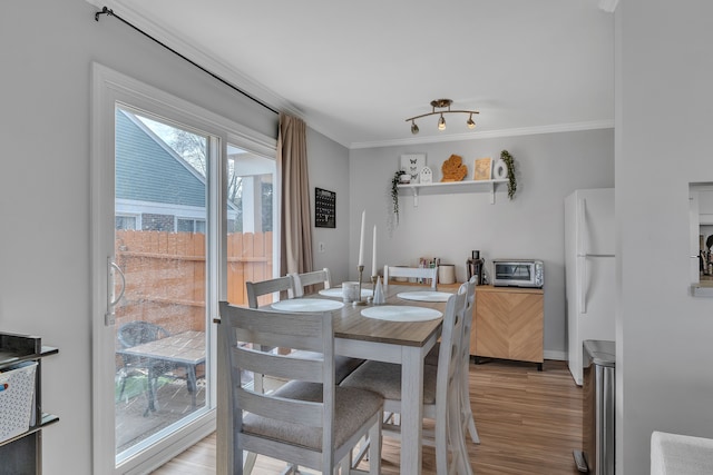 dining room with baseboards, a toaster, light wood-style floors, and ornamental molding