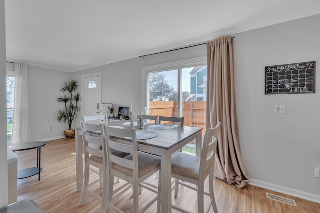 dining area featuring baseboards, a healthy amount of sunlight, visible vents, and light wood-style flooring