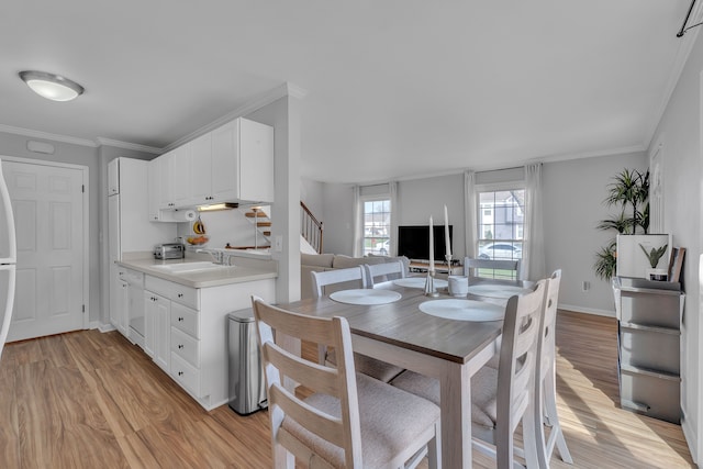 dining area with crown molding, stairs, and light wood finished floors