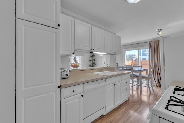 kitchen featuring white cabinets, light wood finished floors, a sink, and white appliances