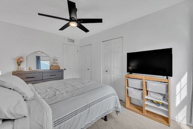 bedroom featuring two closets, visible vents, and ceiling fan