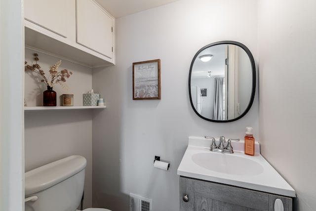 bathroom with toilet, vanity, and visible vents