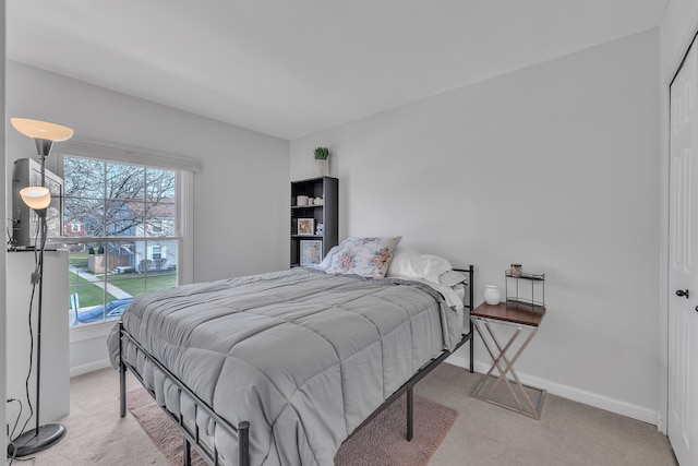 bedroom featuring light carpet and baseboards