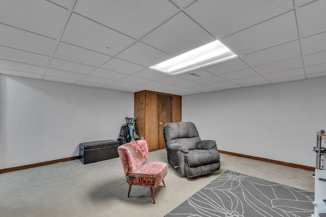 sitting room featuring baseboards, carpet, and a drop ceiling
