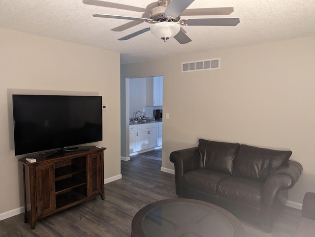 living room featuring ceiling fan, baseboards, dark wood-type flooring, and visible vents