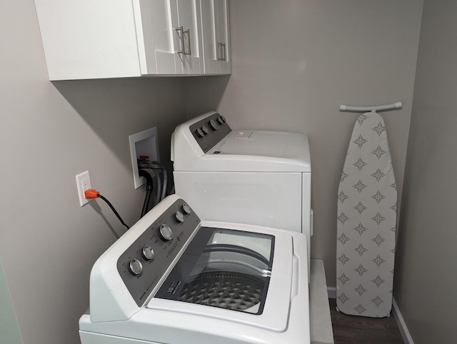 laundry room featuring washing machine and dryer, cabinet space, and wood finished floors